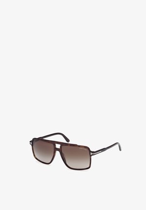 Gafas de sol marrones con un patrón, lentes semitransparentes, forma cuadrada y amplia, acentos metálicos y patillas delgadas grabadas con el nombre de la marca.
