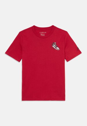 Rood T-shirt met korte mouwen met een kleine afbeelding van een rood, wit en zwart sneaker op de linkerkant van de borst en een klein logo op de rechtermouw.