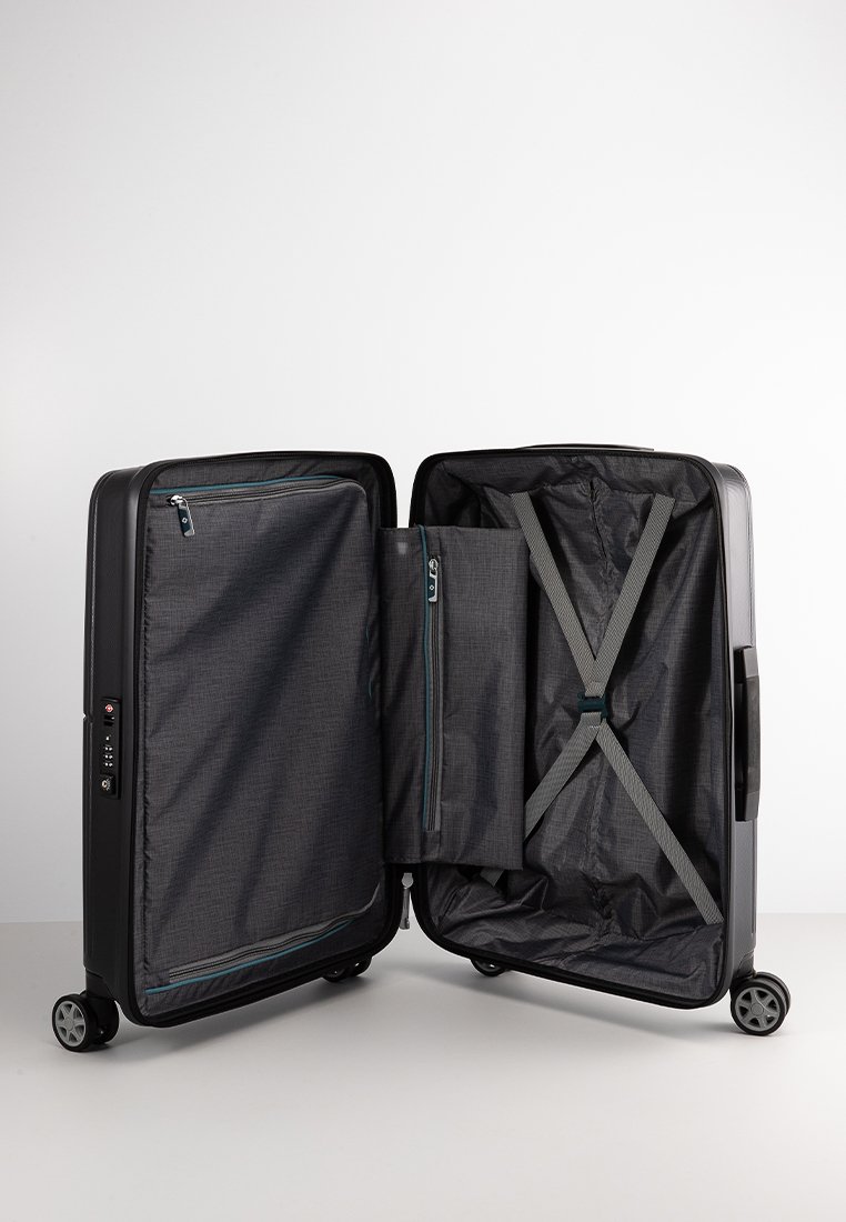 Black hard-shell suitcase with four wheels, open to show zippered compartments and adjustable cross straps inside.