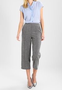 Light blue striped blouse with short sleeves and a ruffled collar, paired with gray crop pants featuring a subtle pattern and a tailored fit.