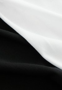 Katoenen stoflagen in zwart, wit en grijs. Glad textuur met een lichte glans, met ribbelpatronen langs de randen.
