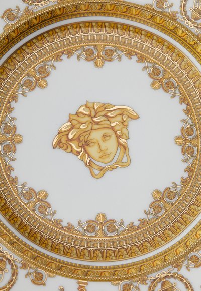 Nádherný talíř se středovým motivem Medúzy obklopený složitými zlatými a bílými barokními dekorativními vzory.