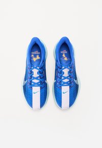 Blaue Sportschuhe mit einem Mesh-Obermaterial, hellblauer Sohle, weißen und pinken Akzenten sowie blauen Schnürsenkeln. Merkmale ein auffälliges Nike-Logo.