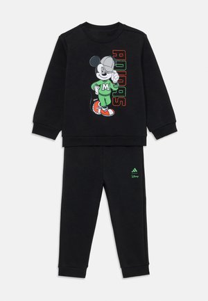Survêtement noir en deux pièces avec un grand graphique de Mickey Mouse sur le haut, accompagné du texte "Adidas" en lettres colorées.