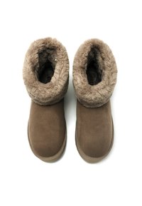 Botas de tobillo de ante marrón con un suave cuello de piel sintética y forro interior. Las suelas son planas y están diseñadas para mayor comodidad.