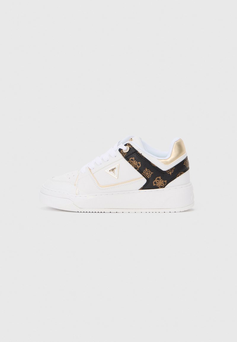 Witte laag uitgesneden sneaker met gouden accenten, zwart patroonpaneel, witte veters en een dikke witte zool op een effen achtergrond.