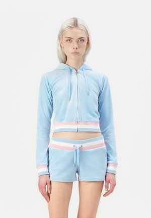 Light blue velour tracksuit with a cropped hoodie and shorts. Features white and pink stripes and front zipper with drawstring waist.