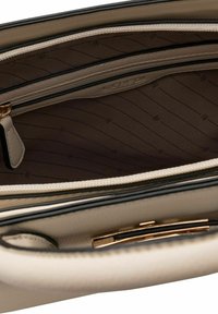Interieur van een beige leren handtas, met een bruine lijnpatroon, een ritszak en gouden accenten. Overal een soepele textuur.