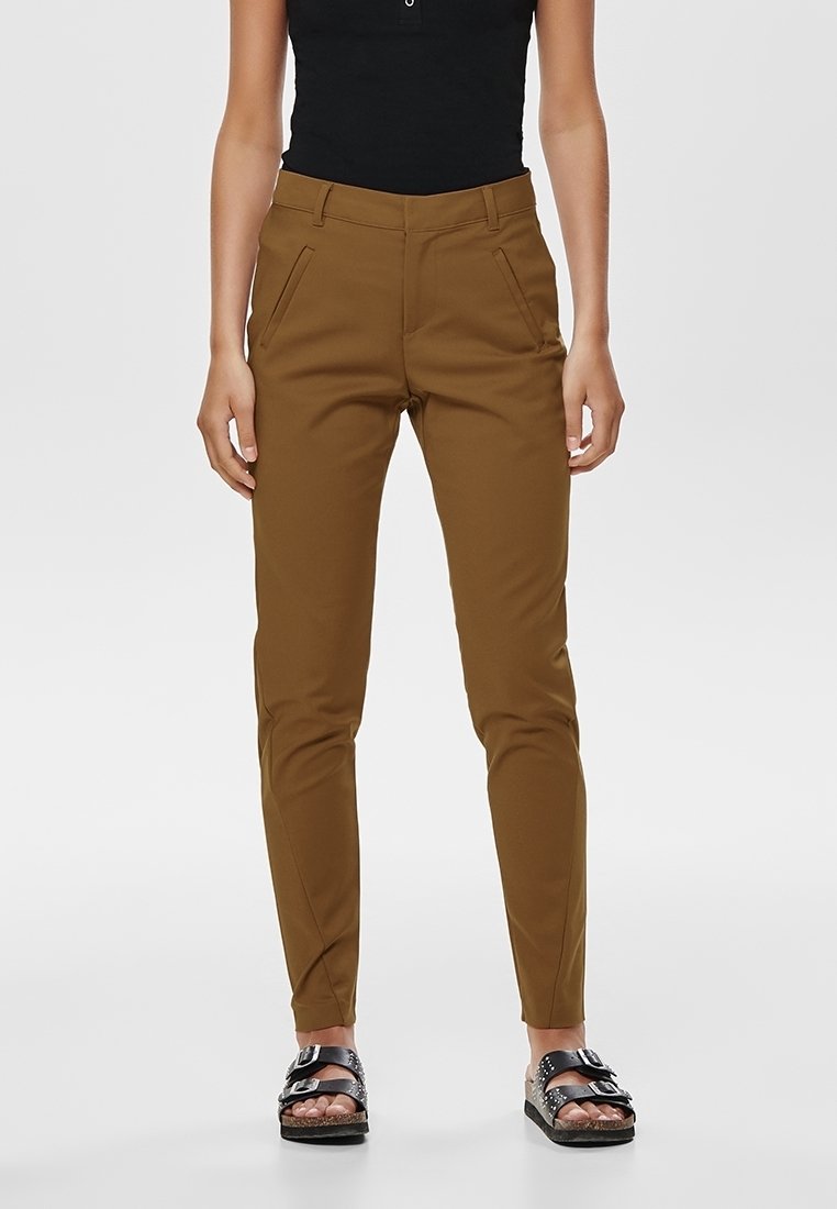 Brown tailored pants with side pockets, slim fit, and smooth texture. Styled with black platform sandals featuring metallic accents.