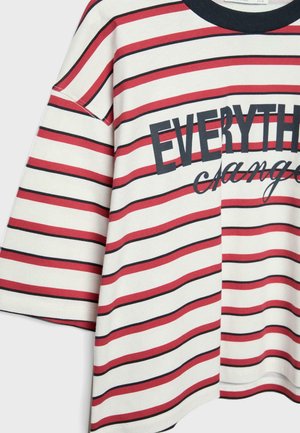 Biele, červené a čierne pruhované tričko s krátkym rukávom, čiernym lemovaním okolo krku a čiastočným textom "EVERYTH" a kurzívou "change" vpredu.