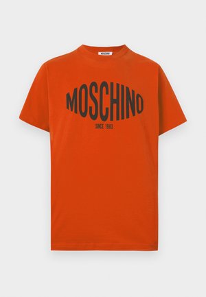 Red cotton t-shirt featuring a bold black "MOSCHINO" logo and "SINCE 1983" text across the chest. Short sleeves and rounded neckline.