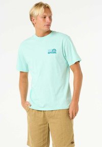Camiseta de algodón de color azul claro con mangas cortas y escote redondo, que presenta un pequeño logo de Rip Curl en el lado izquierdo del pecho.