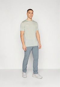 Lichtgrijs sportief T-shirt met korte mouwen en subtiele branding, gecombineerd met lichtblauwe broek met zakken aan de zijkant en een gestroomlijnde pasvorm.