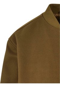 Kaki sweatshirt med en myk, teksturert overflate, rund hals og subtile sømmer langs skuldersømmen. Enkel, moderne design.