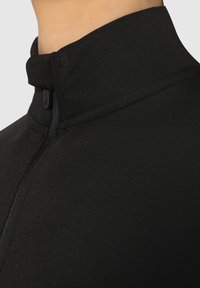 Haut zippé noir avec un col montant, fabriqué en tissu lisse et extensible. Comprend une fermeture éclair discrète et des coutures nettes.