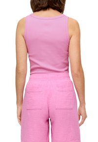 Roze tanktop met een ronde hals, gecombineerd met loszittende, gestructureerde roze shorts met twee achterzakken.