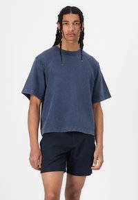 Blå, oversized bomulls T-skjorte med korte ermer og rund hals, kombinert med mørk marineblå shorts. Myk tekstur, uformelt design.