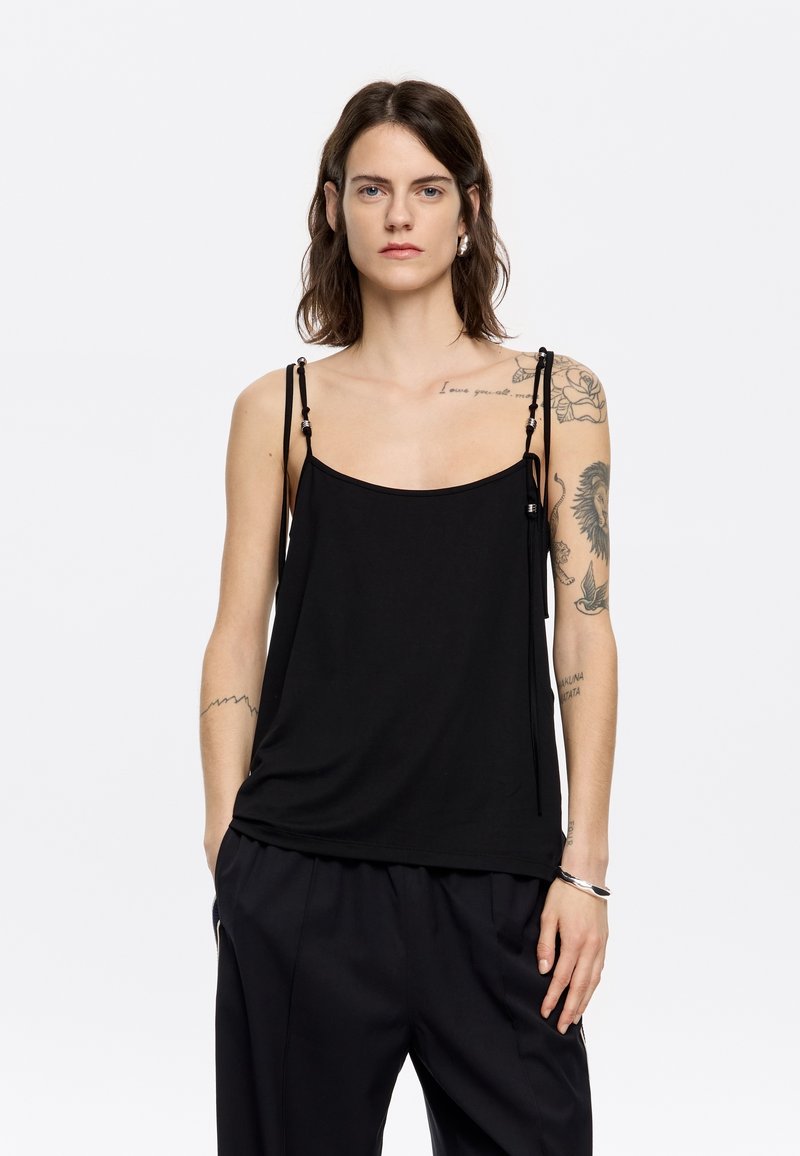 Top in camicia nero con spalline sottili e regolabili, caratterizzato da una vestibilità morbida e un tessuto soffice. Design semplice con dettagli minimi.