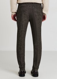 Braune, strukturierte Hose mit maßgeschneiderter Passform, ausgestattet mit Gesäßtaschen und einem geraden Bein, kombiniert mit schwarzen Schuhen.