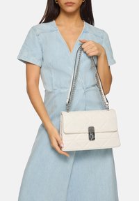 Borsa bianca trapuntata con forma rettangolare, hardware in argento e tracolla a catena, con chiusura a gancio sul davanti.