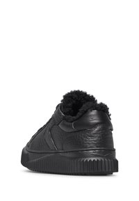Zwarte lederen sneaker met een gestructureerd oppervlak, zachte voering bij de hiel en een geblokt rubberen zool. Eenvoudig ontwerp en ronde vorm.