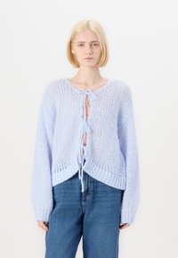Světle modrý oversized pletený cardigan s uzávěrem na zavazování vpředu, s volně tkanou strukturou, žebrovými manžetami a zkráceným lemem.