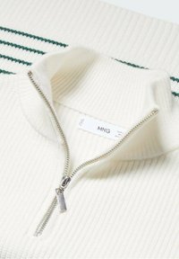 Cremfarbener, gerippter Strickpullover mit halbem Reißverschluss in Silber und grünen Streifen an Kragen und Ärmeln.