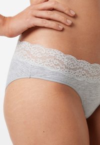 Pilki medvilniniai apatiniai su šviesiai pilku nėriniuotu juosmeniu. Medžiaga yra minkšta, su lygiu paviršiumi, pasižymi banguotu nėriniuotu kraštu ir nematomais siūlais.