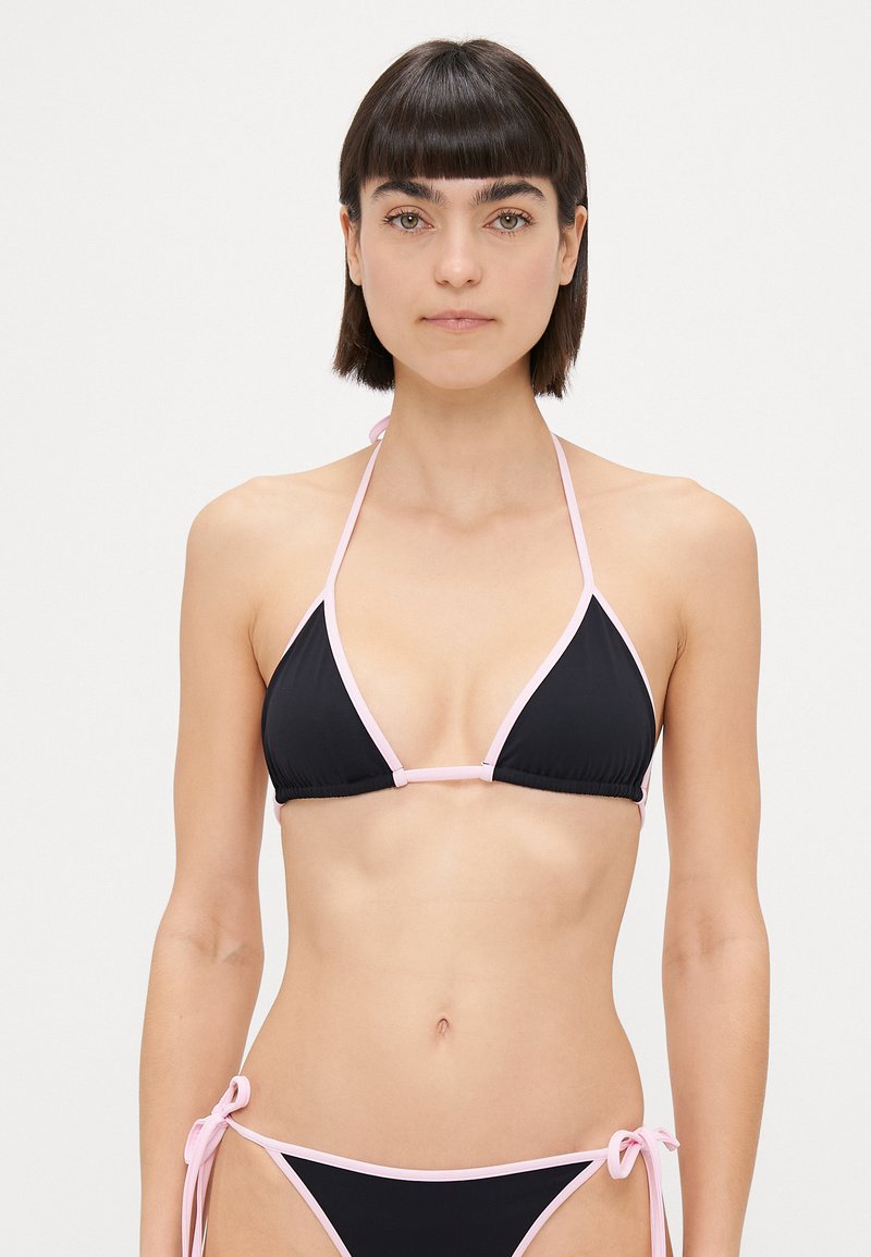Bikini negro con ribete rosa, que presenta un top triangular y una braguita con lazo en los lados. El material parece suave y elástico.