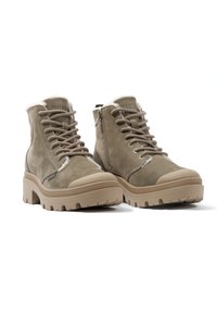 Botas de tobillo de ante color caqui con interior de peluche, puntera redonda y suela de goma beige gruesa; cuentan con cordones y una cremallera lateral para facilitar su uso.
