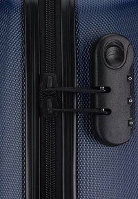 Blauer Polycarbonatkoffer mit strukturierter Oberfläche. Verfügt über einen schwarzen Reißverschluss, doppelte Schlösser und eine runde Griffvertiefung an der Seite.