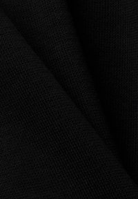 Gros plan d'un tissu noir tricoté plié montrant un motif de tissage texturé détaillé.