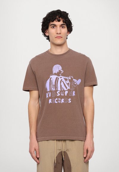 Braunfarbiges Baumwoll-T-Shirt mit einem Grafikmotiv eines Musikers, der Trompete spielt, mit dem Schriftzug "KID SUPER RECORDS" in helllila. Mit kurzen Ärmeln und Rundhalsausschnitt.