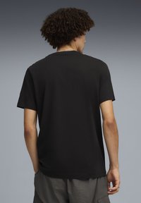 T-shirt en coton noir avec un col rond classique et des manches courtes, présentant un dos uni et une coupe décontractée.