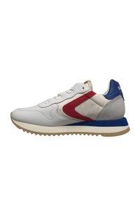 Sneaker bianca con accenti rossi e blu, materiale in pelle liscia, linguetta imbottita e suola in gomma testurizzata con motivo a zigzag.