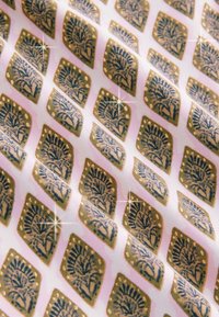 Vzorovaná látka s motivy zlatých a modrých květin na růžovém pozadí, s hladkou texturou a diamantovými designovými prvky.