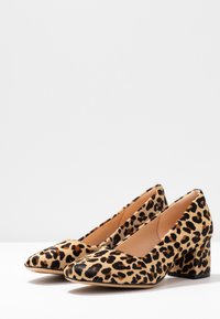Escarpins en imprimé léopard, fabriqués en tissu texturé, avec un bout pointu et un talon noir épais.