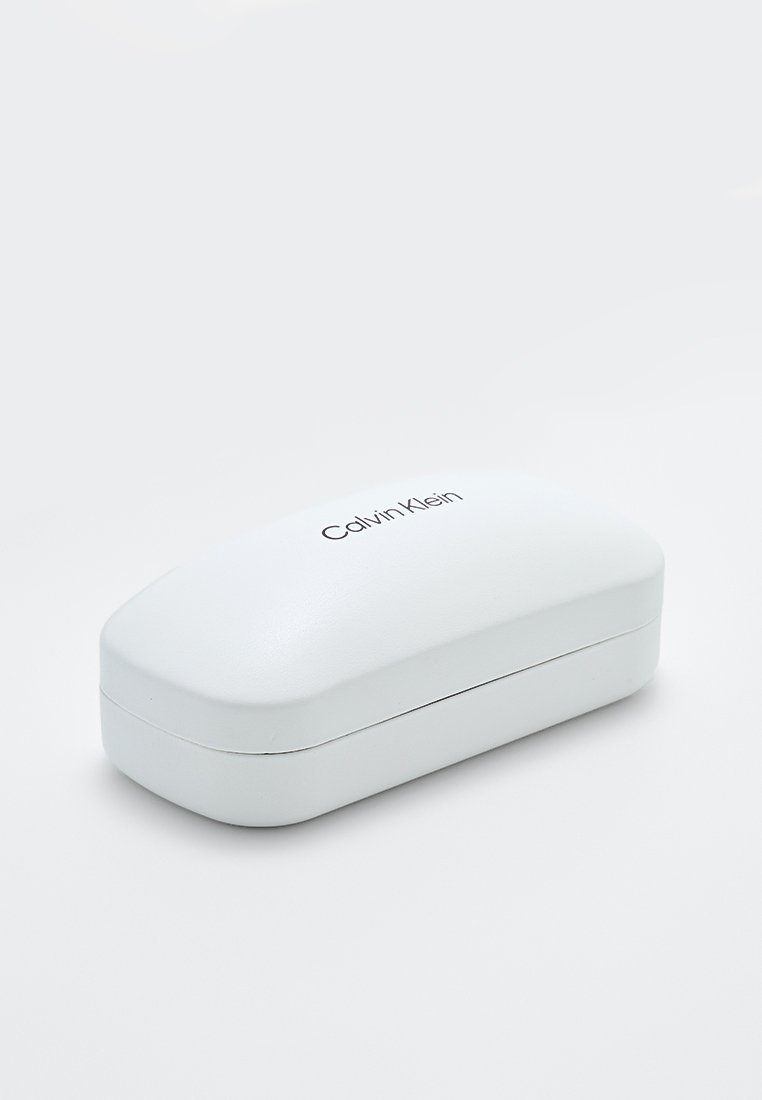 Funda dura rectangular blanca con una textura suave, que presenta un sutil logo de Calvin Klein en la parte superior. Bordes curvados, diseño compacto.