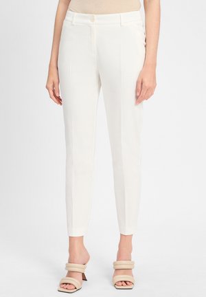 White tailored trousers with a slim fit, made of smooth fabric. Features a button closure and side pockets. Worn with beige heeled sandals.