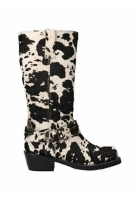 Cowboylaars in zwart-wit koeienhuidpatroon. Heeft een spitse neus, lage hak en een decoratieve riem met metalen accenten.
