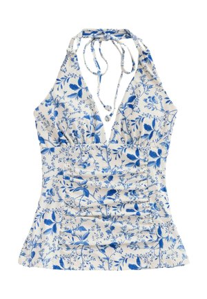 Woman with long dark hair wearing a blue and white floral halter top swimsuit facing away near water.