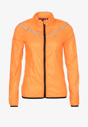 Žena v jasně oranžové bundě na zip, černém sportovním podprsence, černých krátkých legínách a černých běžeckých botách v polovičním kroku.