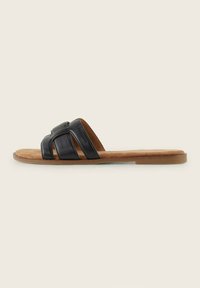 Sandale en cuir noir avec des brides croisées, semelle intérieure marron, semelle en caoutchouc plate, design minimaliste et texture lisse.