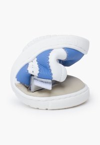 Sneaker blu e bianco con design chiuso, materiale in pelle morbida, suola testurizzata e chiusura con cinturino in Velcro.