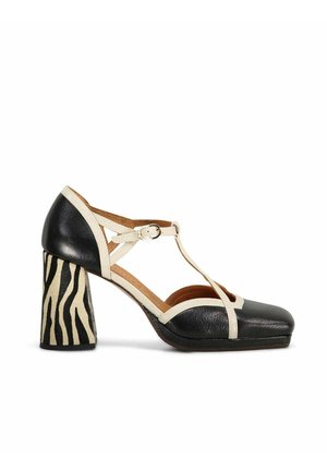 Chaussure à talon haut à bride en T noire et beige avec bout carré et talon bloc, ornée de rayures zébrées noires sur fond beige.