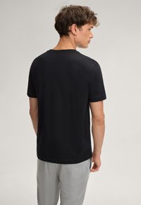 Zwarte T-shirt met korte mouwen en ronde hals, gemaakt van zachte stof. Soepele textuur, minimalistisch ontwerp, geen patronen of logo's.