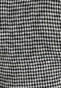 Nahaufnahme von schwarz-weißer karierten Stoff mit geraffter, elastischer Textur, die kleine gewölbte Quadrate bildet.