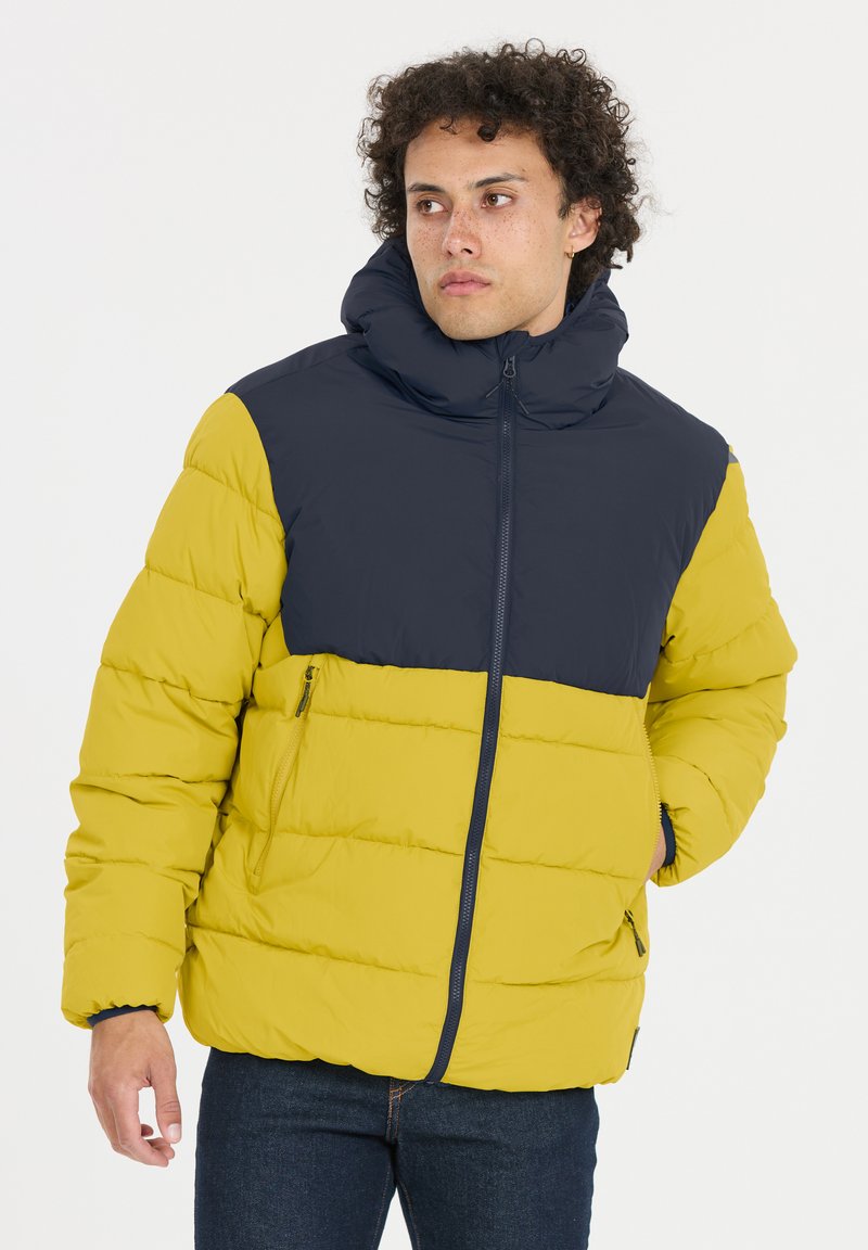 Puffjacka med färgblockering i gult och marinblått, hög krage, dragkedjefickor och quiltad textur. Tillverkad av lätt, isolerande material.