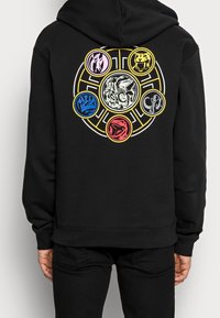 Svart huva med en cirkulär grafik på baksidan som har färgglada djurikoner: röd, blå, rosa, gul och svart på en vit bakgrund.