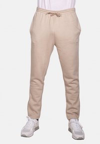 Pantaloni da jogger beige realizzati in materiale morbido, con vita regolabile tramite cordino, tasche laterali e design slim fit. Piccolo logo sul gambale.